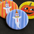 A round pinback button featuring a ghostie clown with a blue striped background. The pin is surrounded by other pin designs.