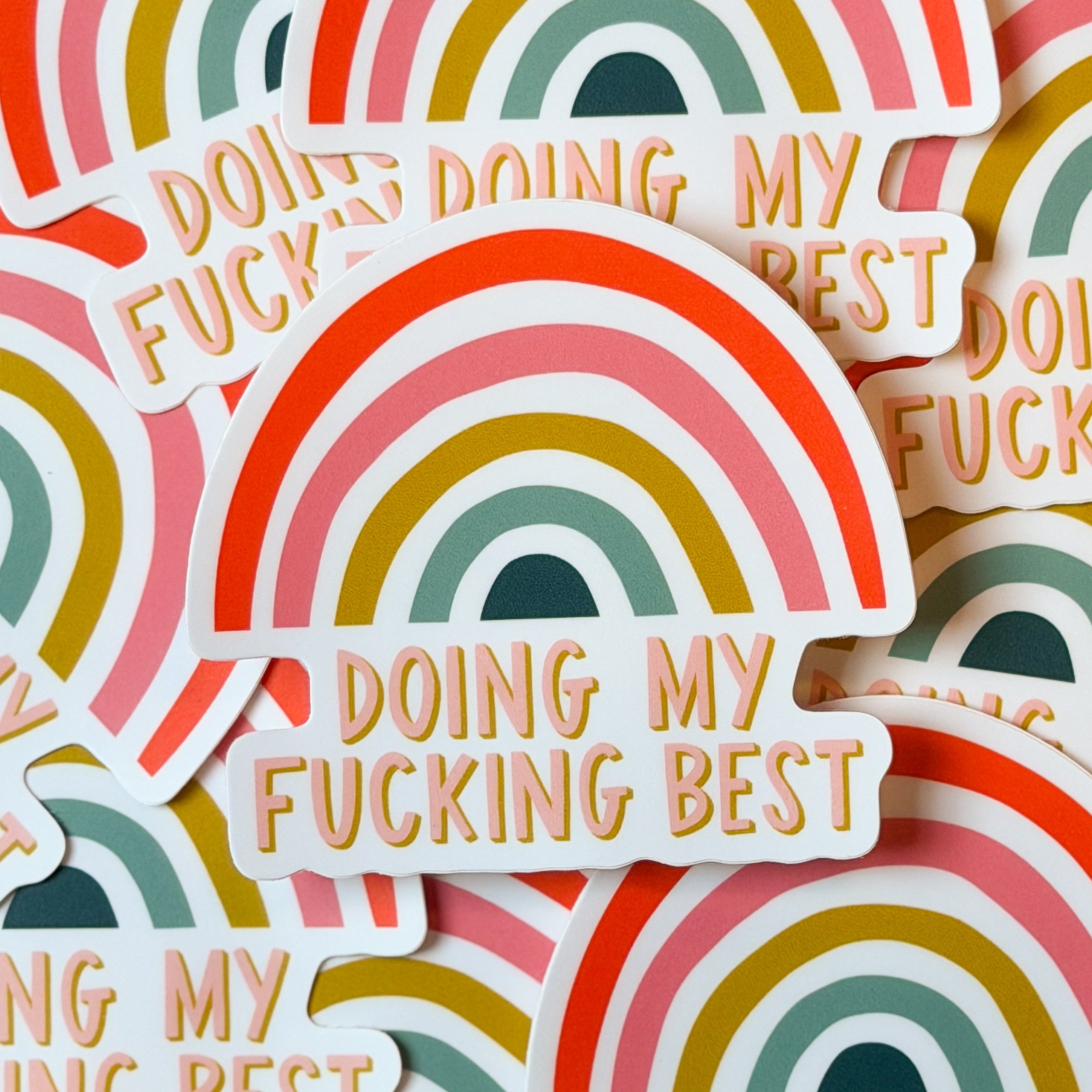A pile of rsainbow sticker with 'DOING MY FUCKING BEST' written on the bottom.