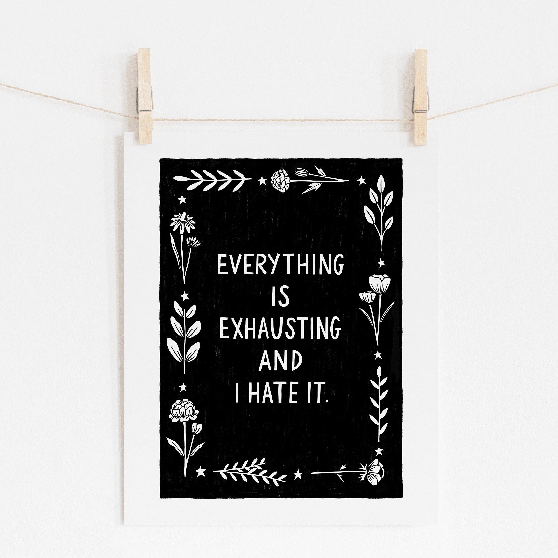 An 8x10 art print that says 'EVERYTHING IS EXHAUSTING AND I HATE IT.' in white on a black background, surrounded with white flowers and stars.