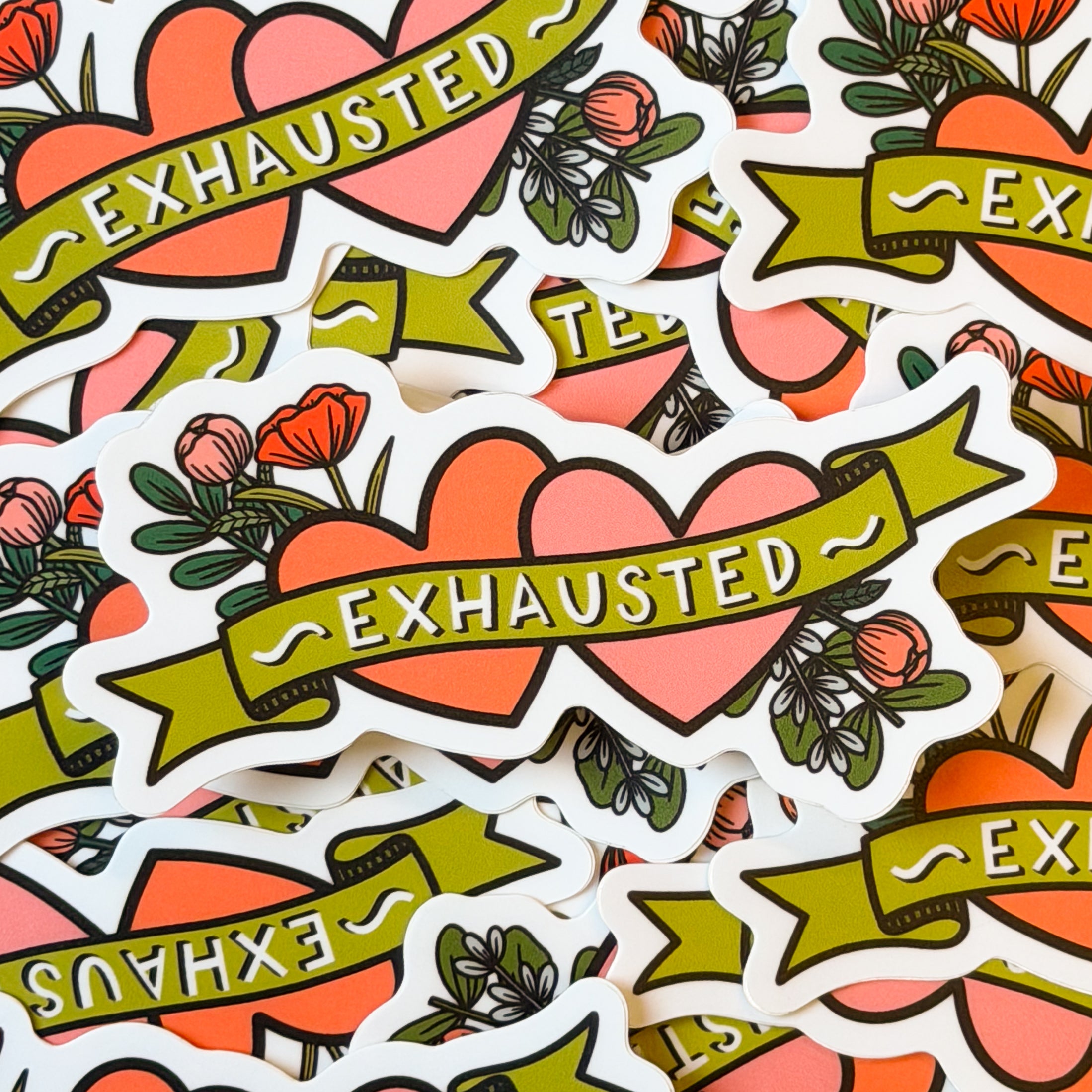 A pile of stickers with two hearts and flowers with 'exhausted' written across it.