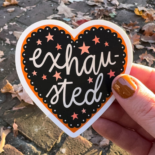 A heart-shaped sticker with 'exhausted' text and star patterns on a black and orange background.