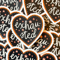 A pile of heart-shaped stickers with 'exhausted' text and star patterns on a black and orange background.