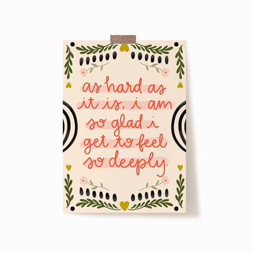 A 5x7 art print with a cream background. It says 'as hard as it is, i am so glad i get to feel so deeply.' in red with embellishments of flowers and leaves as a border.