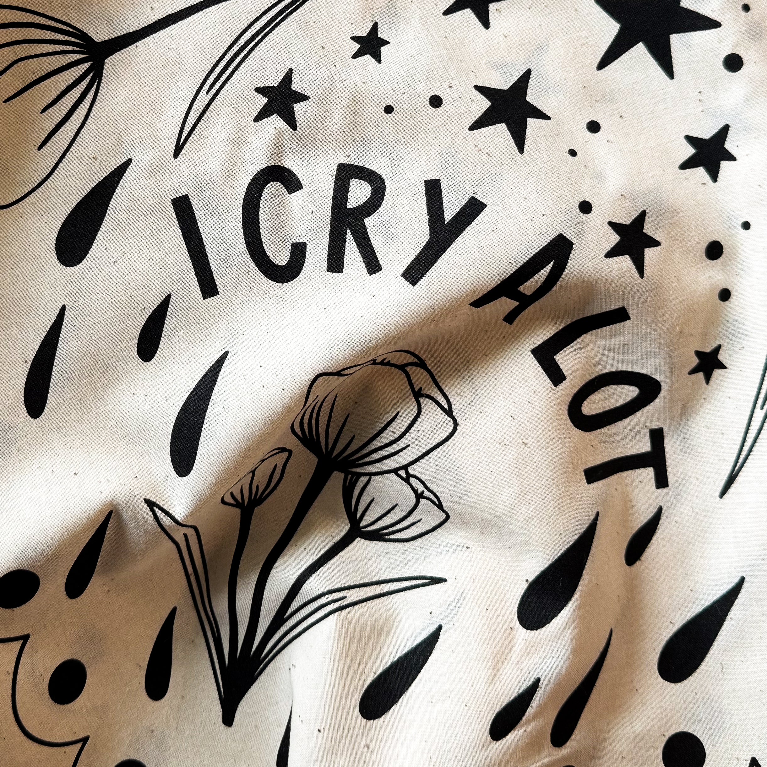 Natural color bandana with black floral patterns and 'I CRY A LOT' text.
