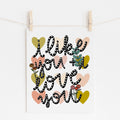 An 8x10 art print that says 'i like you + i love you' in black and white with flowers and hearts printed in the background.
