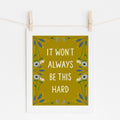 An 8x10 art print with yellow background that says 'IT WON'T ALWAYS BE THIS HARD' in cream surrounded by cream and blue flowers.