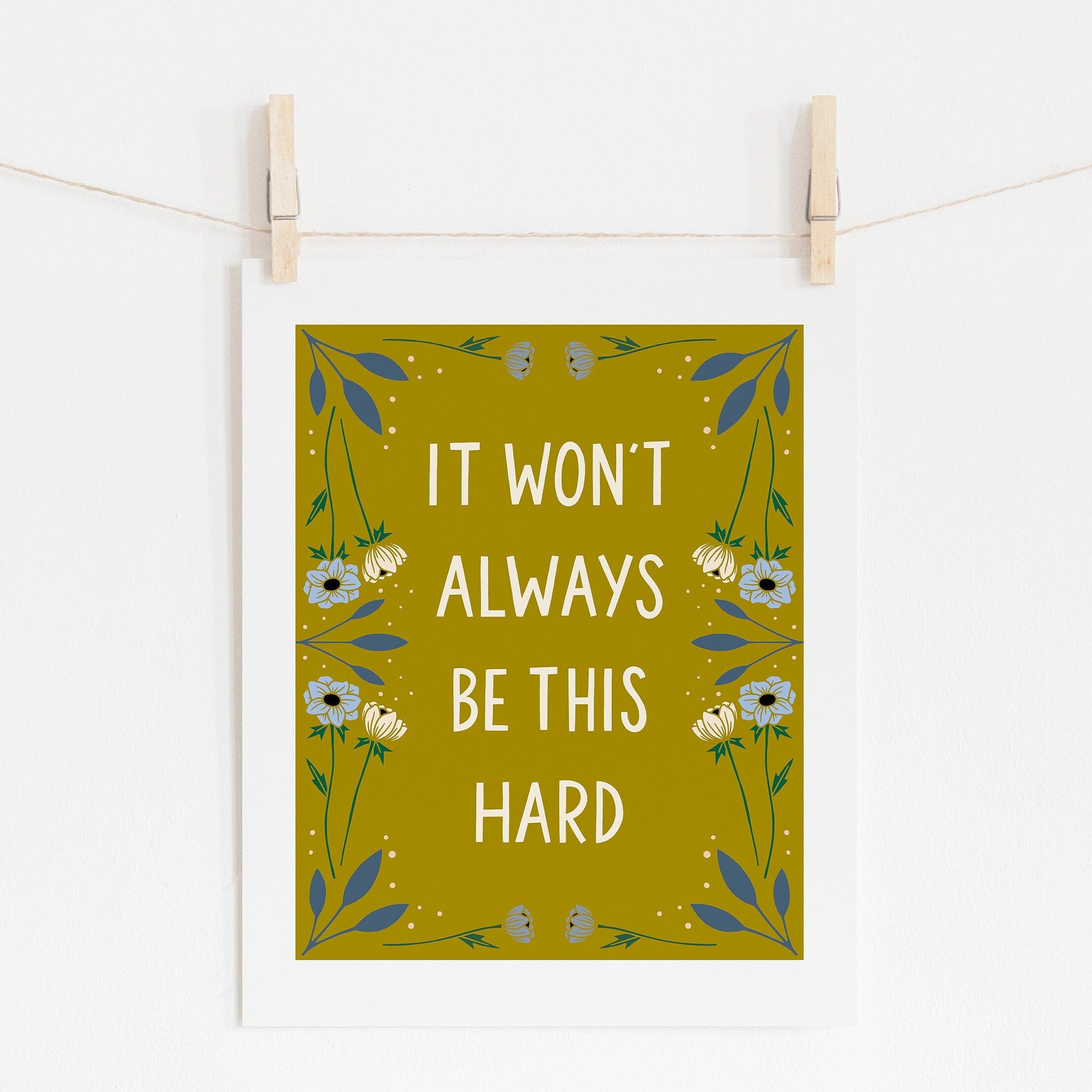An 8x10 art print with yellow background that says 'IT WON'T ALWAYS BE THIS HARD' in cream surrounded by cream and blue flowers.