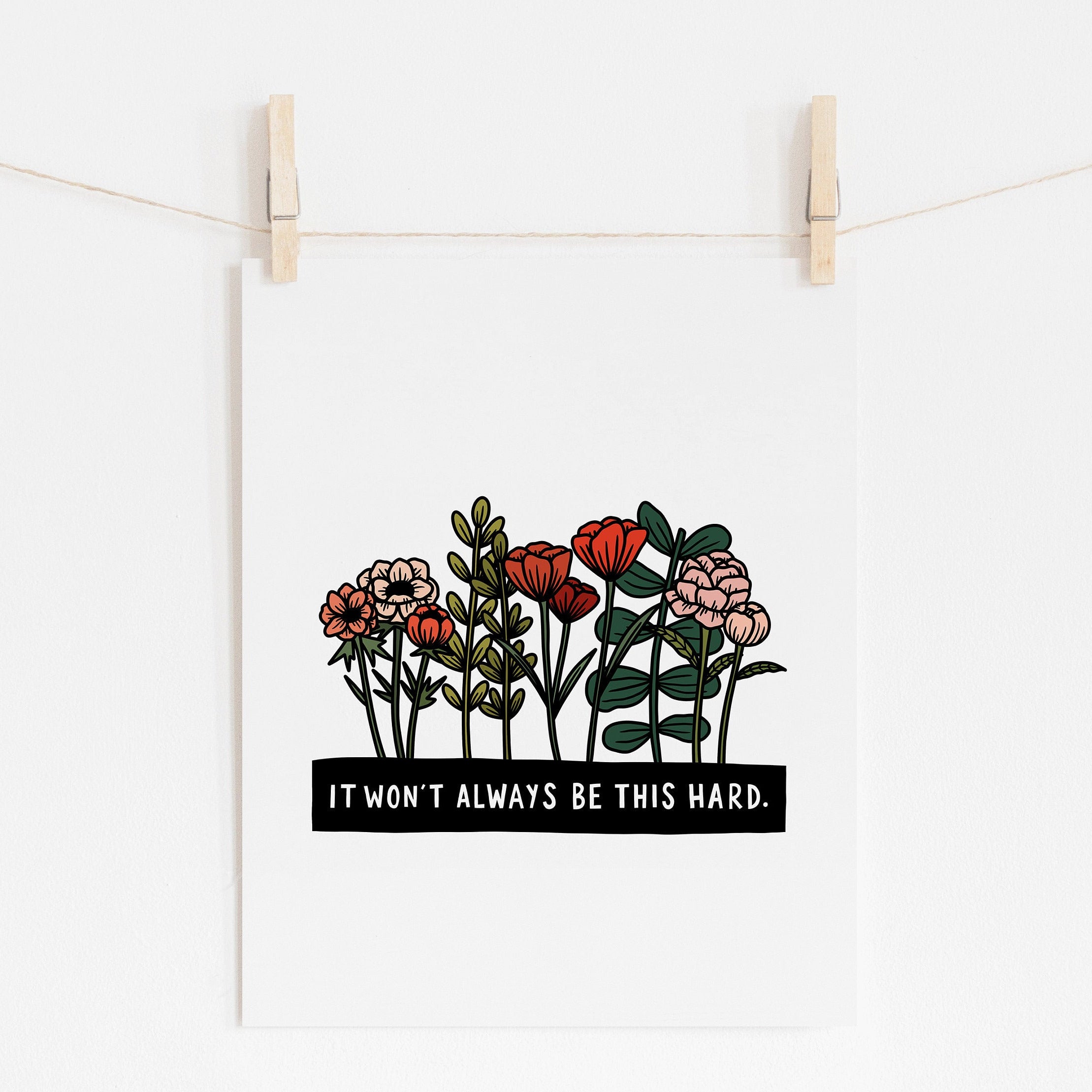 An 8x10 art print that says 'IT WON'T ALWAYS BE THIS HARD.' in white on a black rectangle. A bunch of flowers grow out of the black rectangle.