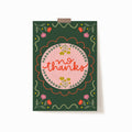 A 5x7 art print with a dark green background that says 'no thanks' on a pink circle surrounded by embellishments and flowers.
