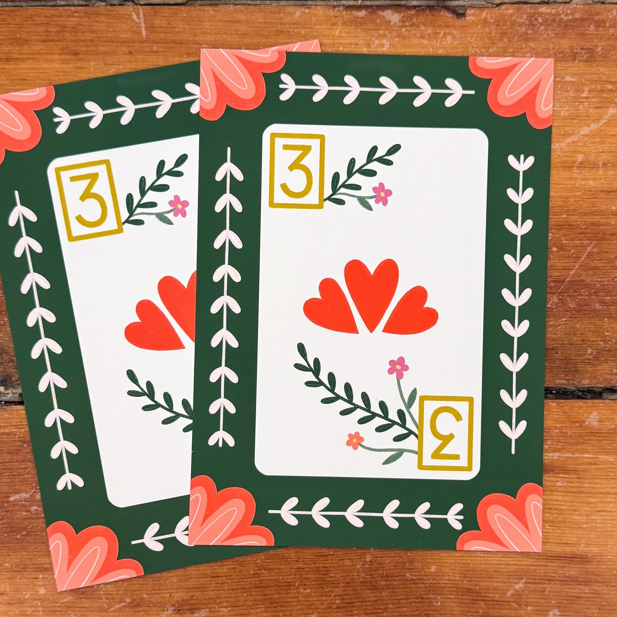Two 5x7 art prints  of a 3 of hearts playing card with florals and a green background and peach corner embellishments.