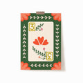 A 5x7 art print of a 3 of hearts playing card with florals and a green background and peach corner embellishments.