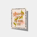 A mockup of a greeting card with 'thank you FOR BEING YOU' in orange text with a peach flower background and border of little black flowers.