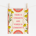 An 8x10 print that says 'THERE IS STRENGTH AND POWER IN COMMUNITY' surrounded by yellow flowers and red embellishments.
