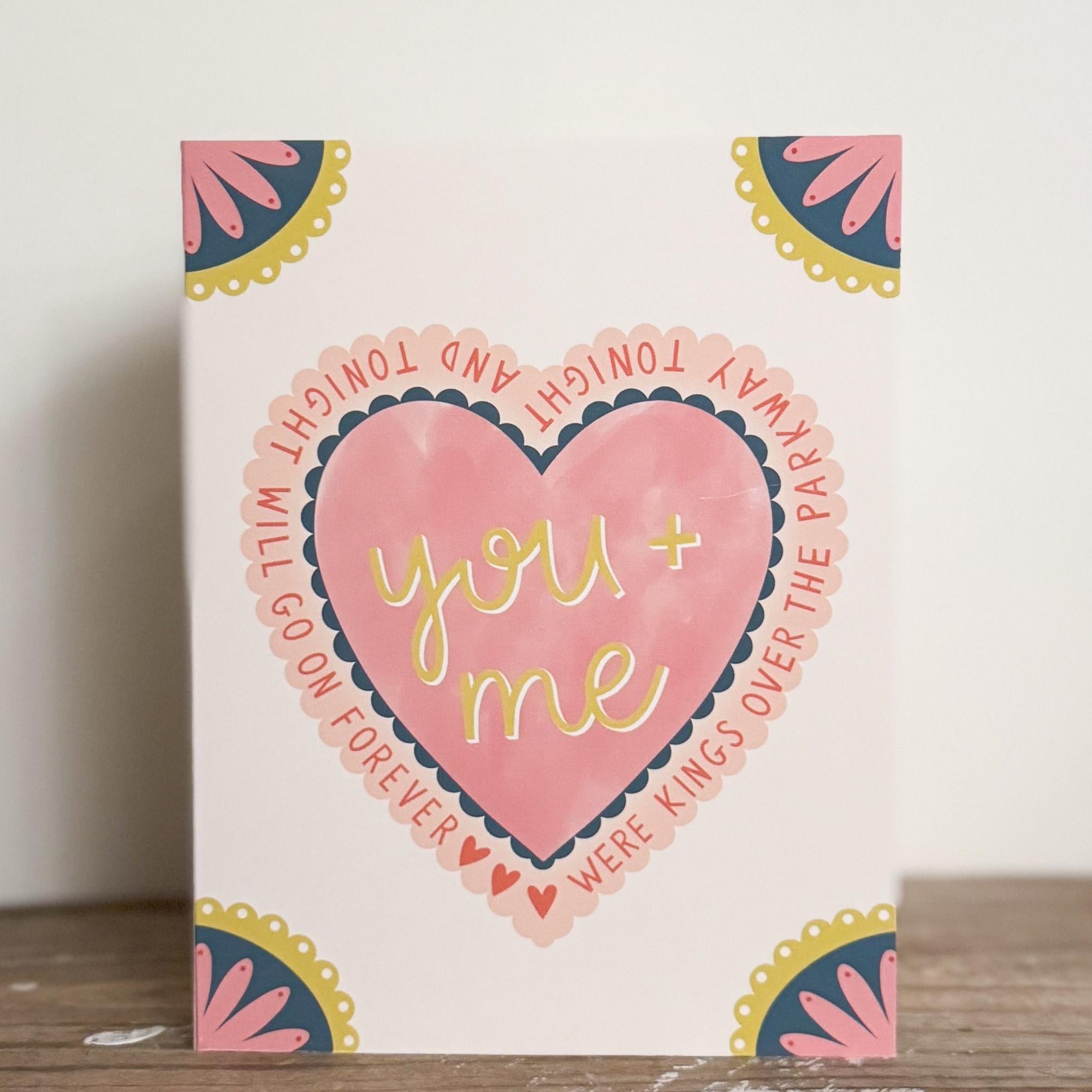 A greeting card with a heart in the middle that says 'you and me were kings over the parkway tonight and tonight will go on forever' with three small hearts to fill space. All four corners are embellished with a scalloped flower.