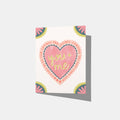 A mockup of a greeting card with a heart in the middle that says 'you and me were kings over the parkway tonight and tonight will go on forever' with three small hearts to fill space. All four corners are embellished with a scalloped flower.